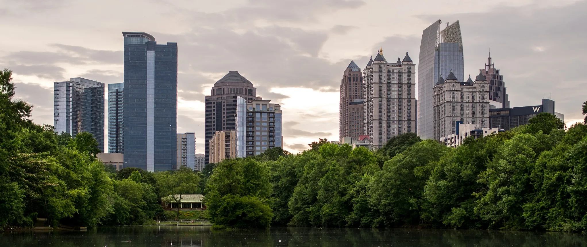The Midtown Atlanta skyline at golden hour, mirrored across Lake Clara Meer in Piedmont Park
