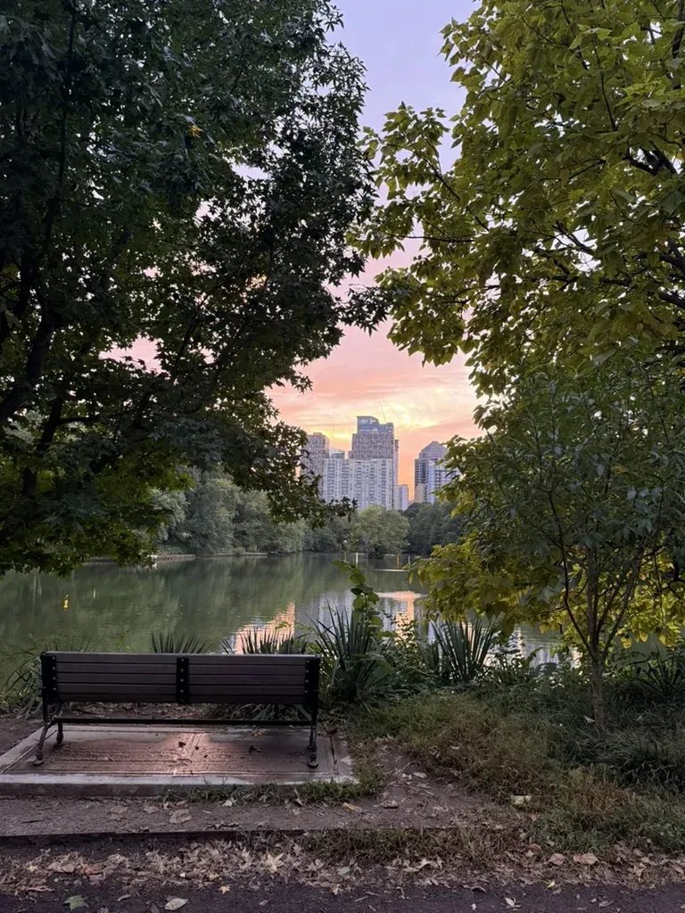 A bench overlooking the lake and Midtown skyline in Piedmont Park at sunset